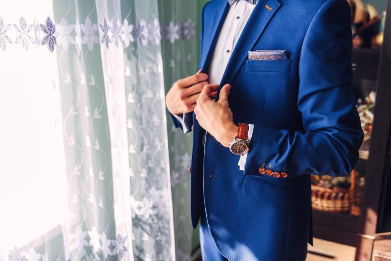 A man in a very nice blue suit stood in front of a window