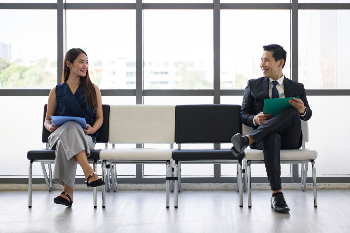 A woman and a man sat at opposite ends of an indoor bench