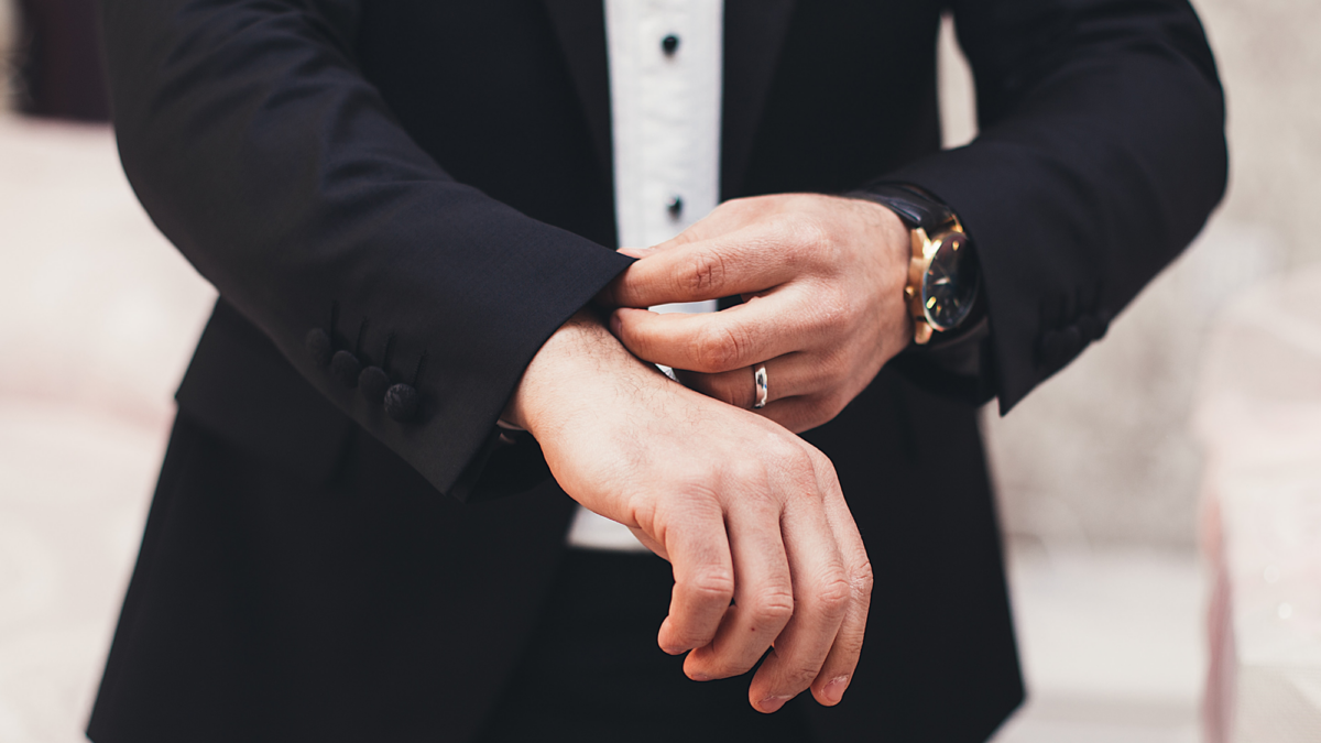 A man in a tuxedo checking his cufflinks