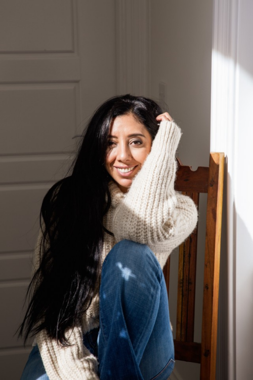 Leena Parmar in a comfortable jumper sat in a chair with the sun in her face