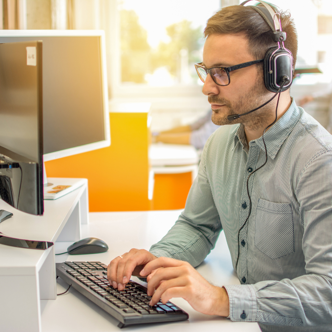 A man with a headset working at a desk