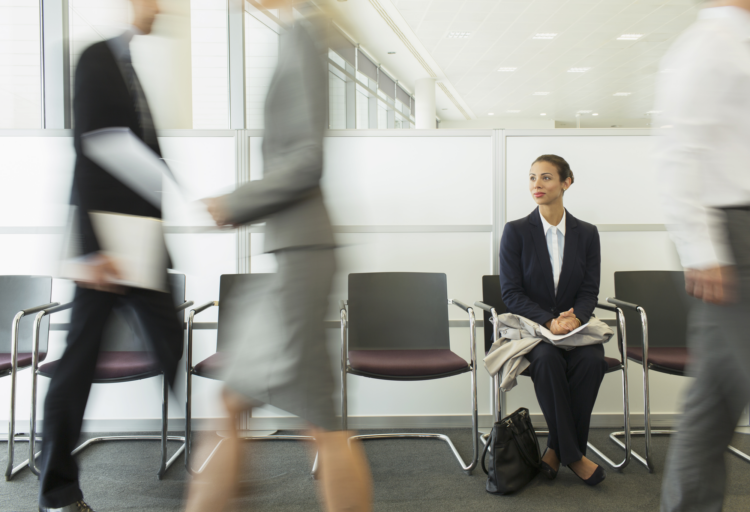 A woman sat at a chair in a busy office