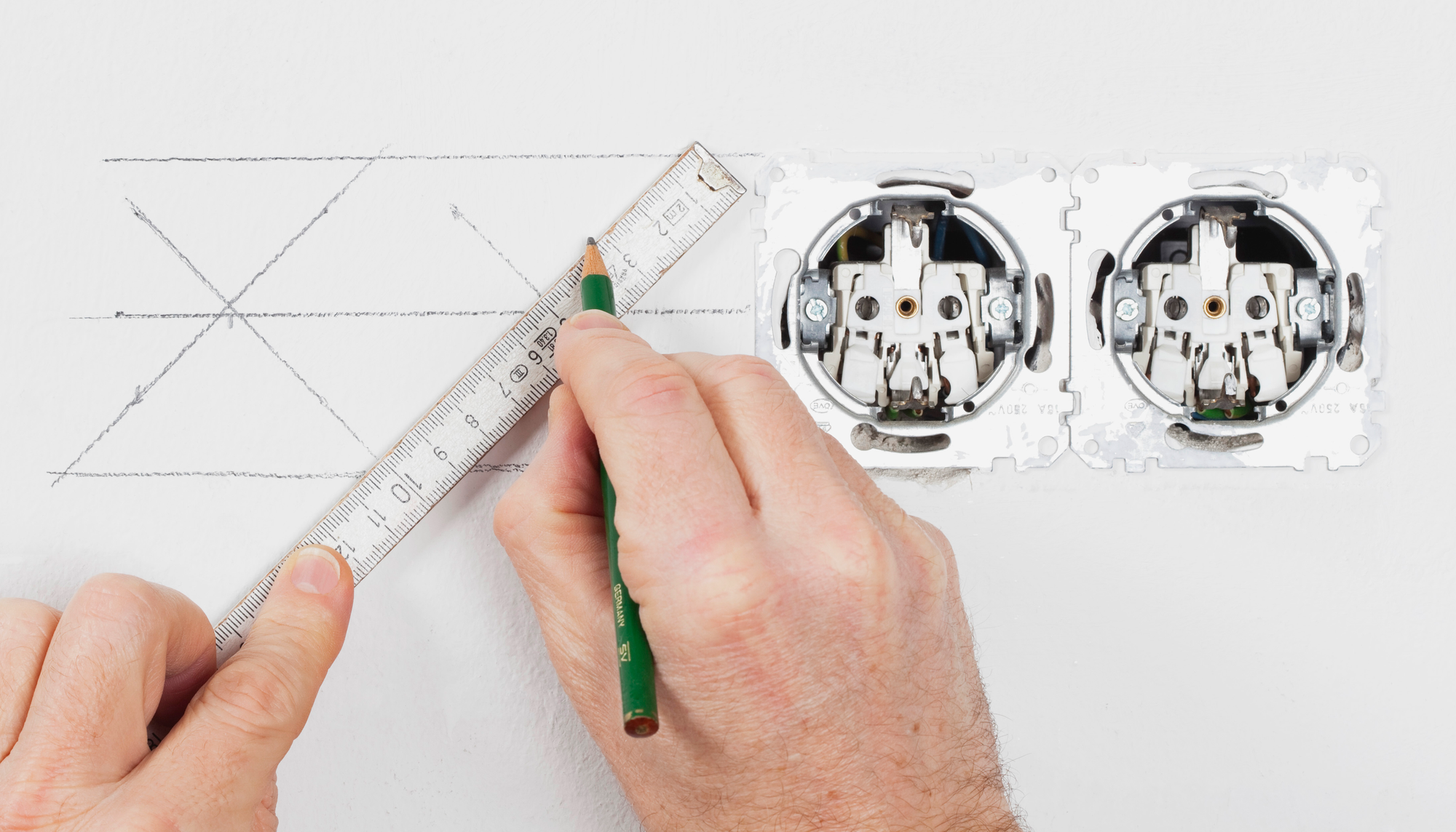 A man drawing an outline of where electric circuit will go on a wall
