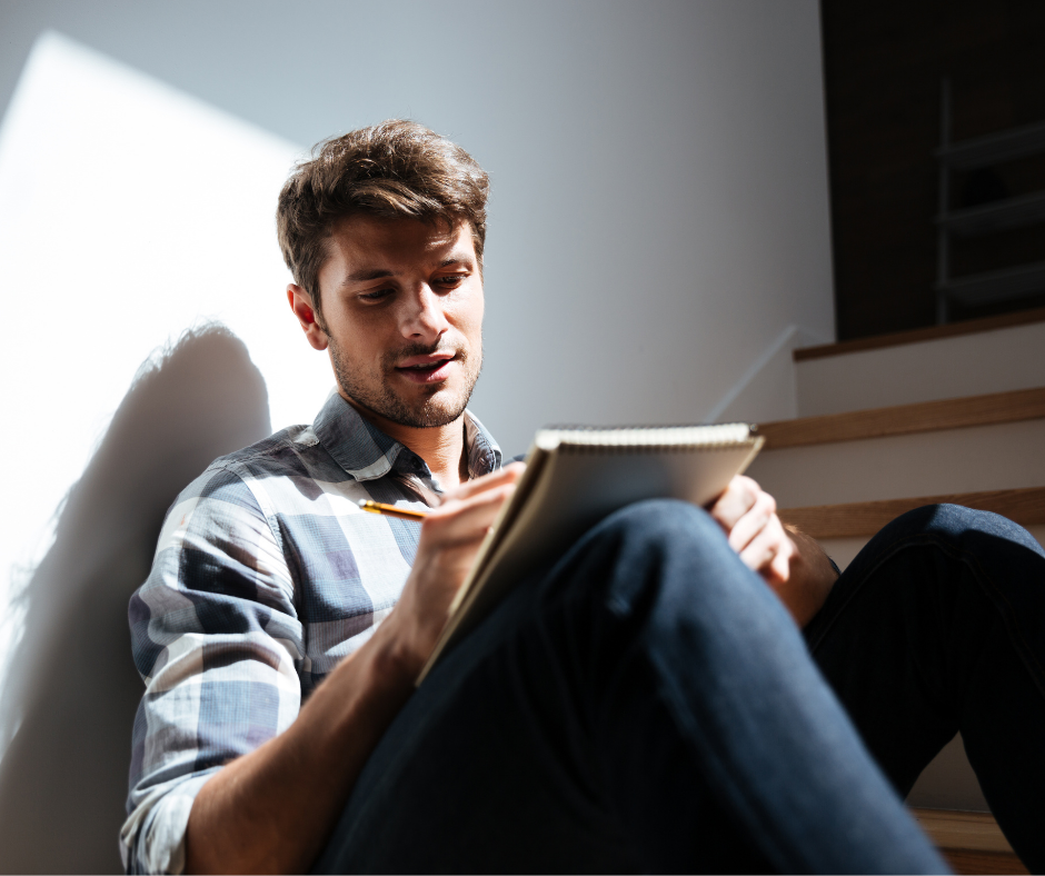 A man sat on stairs writing on a laptop