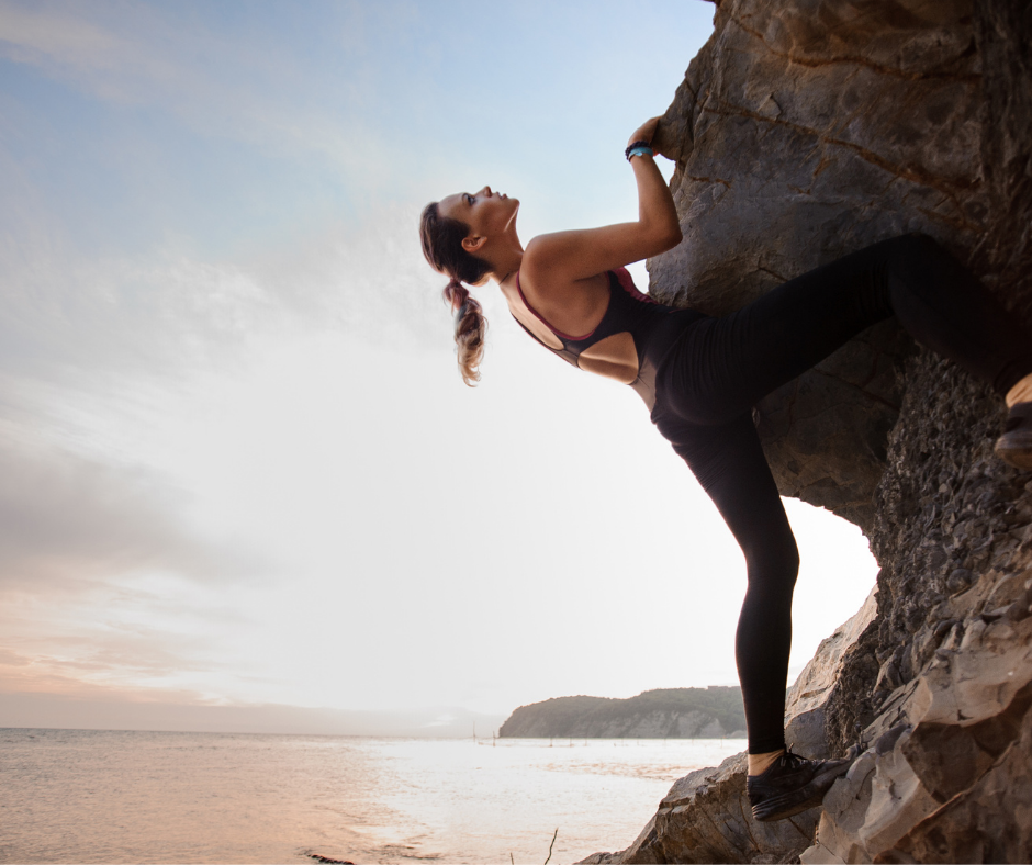 A woman rock climbing by the sea