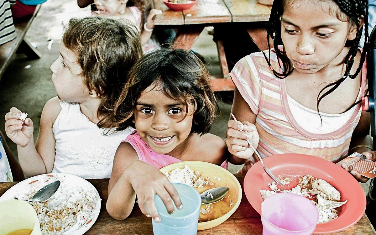 A group of children eating at a picnic bench