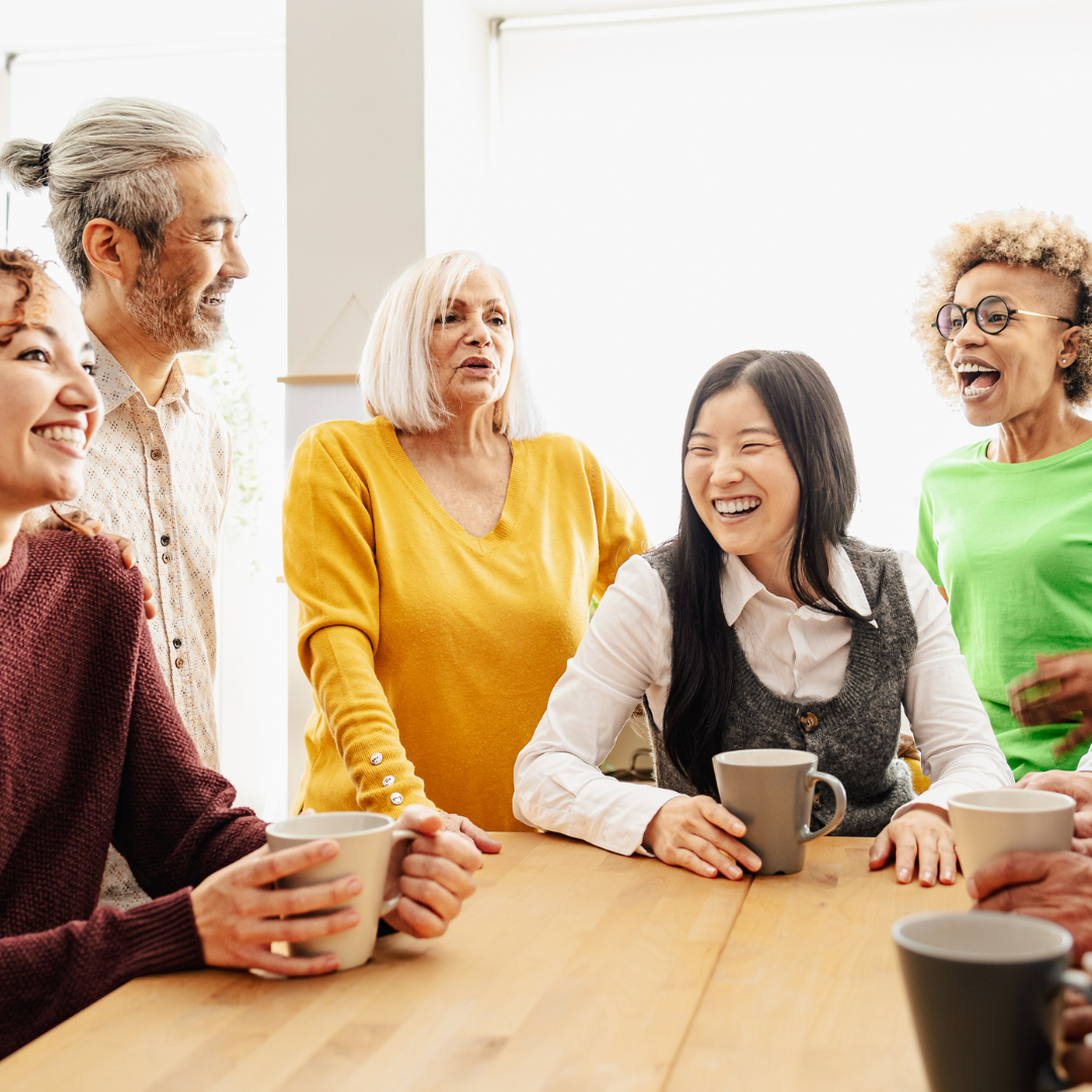 A group of people stood around a table drinking coffee