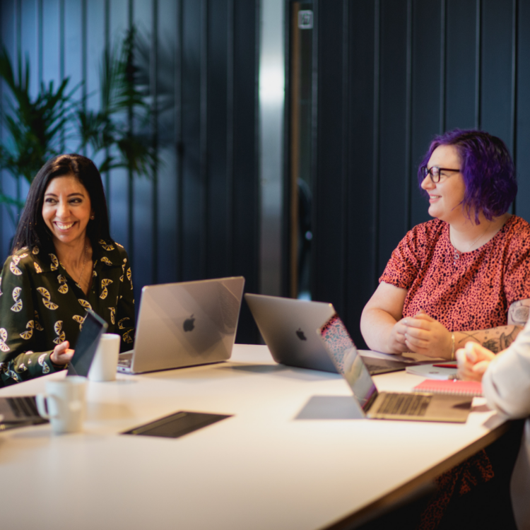 A couple of women working on a table with laptops