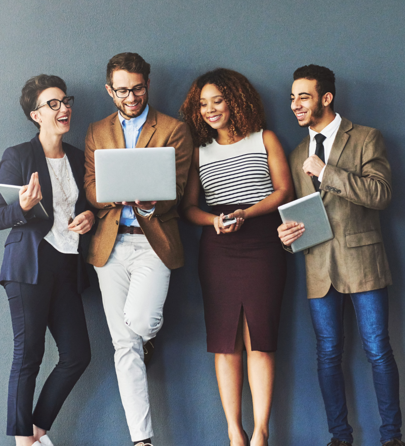 A diverse group of people standing against a wall with laptops showing the power of local team.