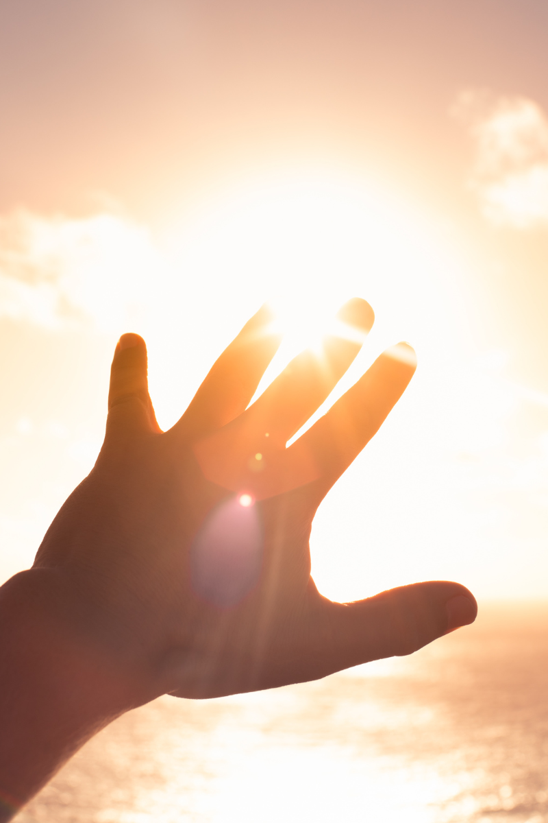 A hand reaching out to the sun