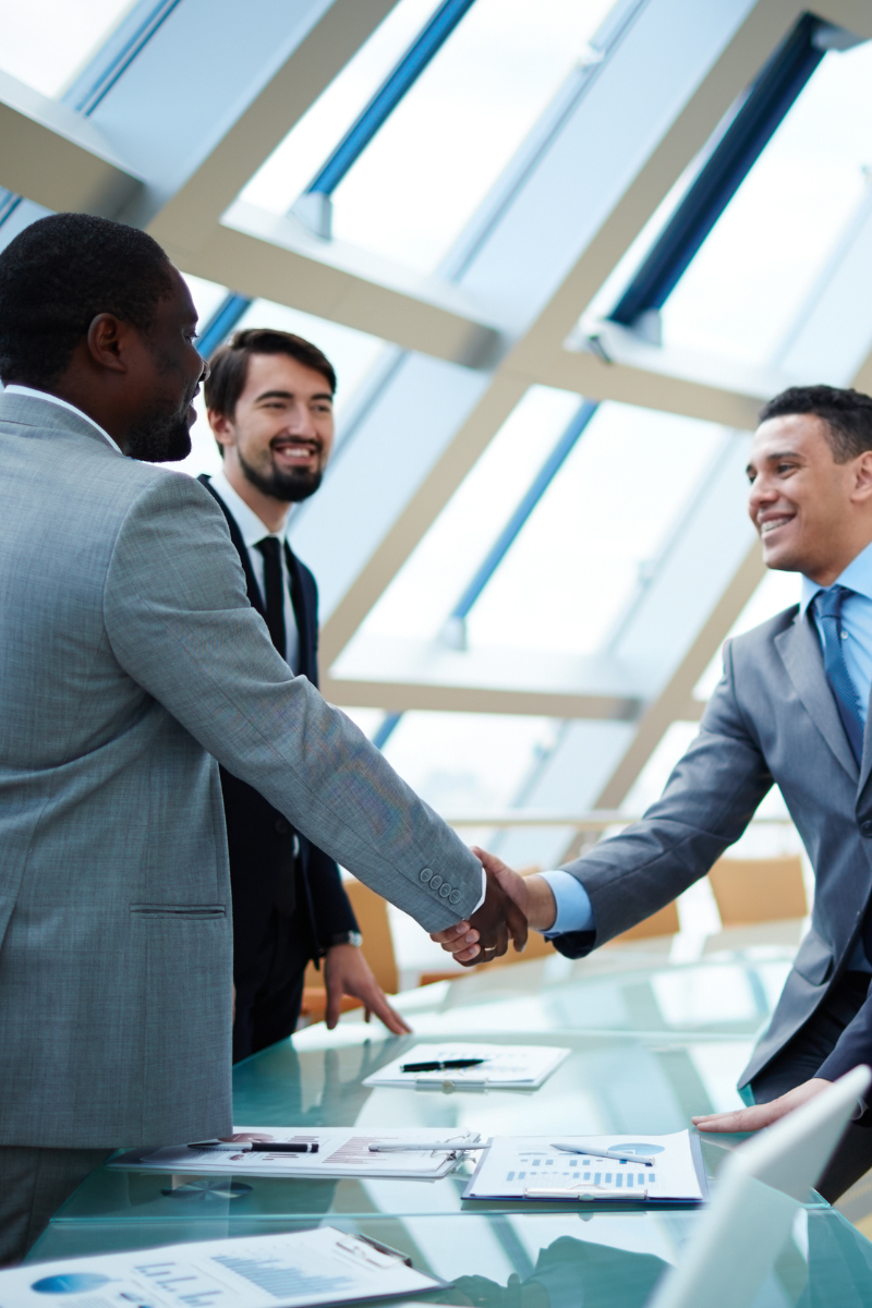 Two professionals shaking hands in an office environment.